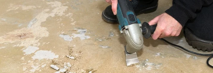 Person entfernt Bodenbelag mit Multitool.